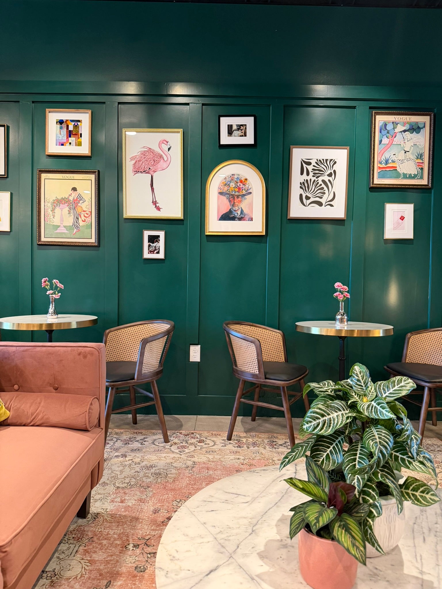 Cozy interior with green walls, framed art, and a pink sofa.