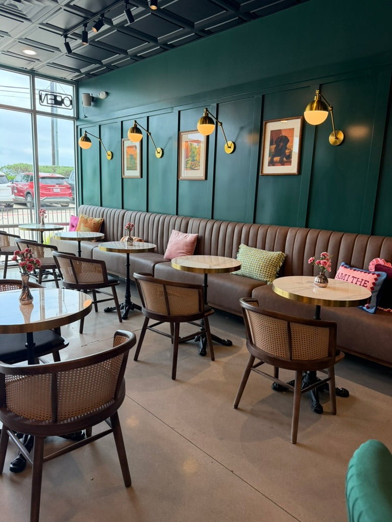 Interior of a modern cafe with green walls, wooden furniture, and decorative elements.